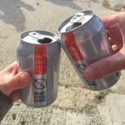 A close up of two cans of Hobo Beer + Co. lagers. Rob and Emma are saying Cheers!