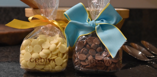 A photograph of some Godiva white and milk chocolate buttons in separate bags with yellow and blue ribbons