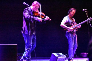 A photograph of musicians Holder & Smith playing the violin and guitar on stage