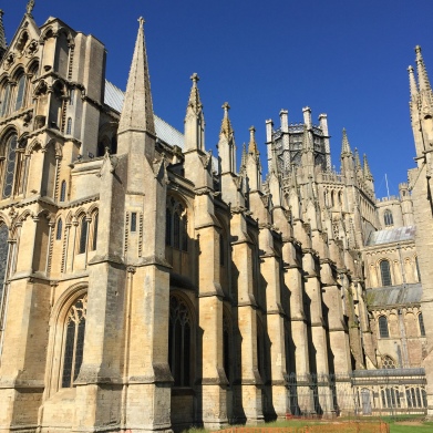 A photograph from low down at the eastern end of Ely Cathedral with brilliant blue sky above and shadow definition along the building