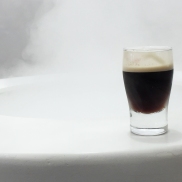 A photograph of a Guinness shot glass on the right side of the photo with white tones in the rest of the photograph to demonstrate negative space and rule of thirds