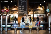 A photograph of seven beer taps, just a small selection of what they offer. Photo by Tom Gold.